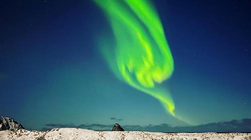 Vakkert nordlys over jorden mot blå himmel i bakgrunnen.